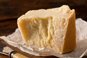 An aged authentic parmigiano reggiano parmesan cheese with wrapper and cheese knife.